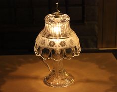 a glass table lamp with a lit candle on top