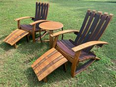 three wooden lawn chairs sitting on top of a grass covered field next to a small table