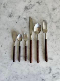 five forks, two spoons and one knife on a marble surface