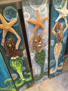 three mermaids and two starfish are painted on wood panels in the shape of seashells