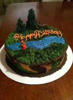 a birthday cake is decorated with grass and trees