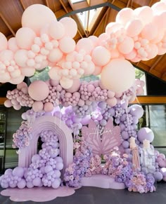 an elaborate balloon arch is decorated with pastel balloons and lavender hues for a princess themed birthday party