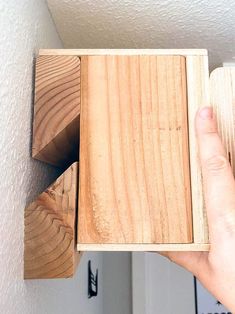 a person holding a wooden object in their right hand and another piece of wood sticking out of the wall