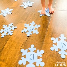 a child's feet standing on the floor with cut out snowflakes