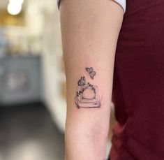 a woman's arm with a small tattoo of a cake and butterflies on it