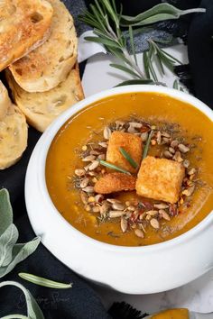 a white bowl filled with soup next to some bread