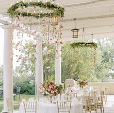 an outdoor wedding venue set up with white linens and pink flowers hanging from the ceiling