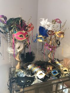 two masquerade masks sitting on top of a glass shelf next to each other