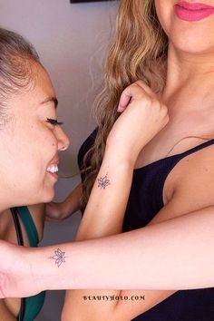 two women with tattoos on their arms looking at each other