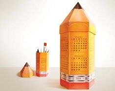 an orange pencil holder with two different colored pencils in it and another one that is shaped like a rocket