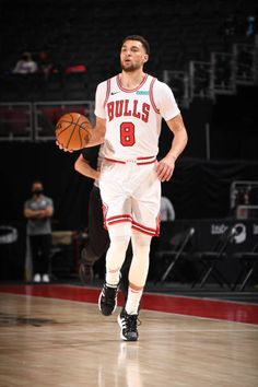 a basketball player dribbling the ball down the court with one foot and his other hand