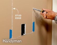 a man is painting the wall with blue tape