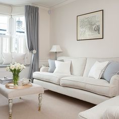 a living room filled with furniture and a window covered in curtains next to a white couch