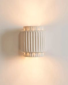 a white wall mounted light on the side of a wall next to a lamp shade