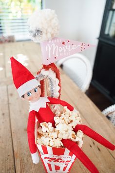 an elf is sitting in a popcorn bucket