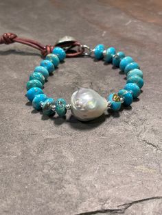 "Exquisite 10mm AAA Kingman Turquoise paired with sterling silver beads and featuring 1 AAA Baroque Pearl. Finished with a handmade Hill Tribe Silver button and leather loop closure points at 7\" and 8\". Will fit wrists 6.5\" - 7.5\". Your turquoise beauty will arrive in my signature logo box, ready for gifting or safe keeping. Thanks so much for stopping by today, and for supporting small, artisan, and handcrafted goods businesses." Adjustable Turquoise Bohemian Pearl Bracelet, Handmade Adjustable Turquoise Pearl Bracelet, Artisan Turquoise Bracelets With Natural Stones, Artisan Turquoise Hand-strung Bracelets, Handmade Blue Bohemian Pearl Bracelet, Bohemian Turquoise Pearl Bracelet With Round Beads, Bohemian Bracelets With Sterling Silver Clasp And Round Beads, Handmade Turquoise Pearl Bracelet With Round Beads, Artisan Turquoise Beaded Bracelet