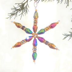 an ornament hanging from a christmas tree with beads and crystals on it's sides