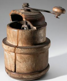 an old fashioned coffee grinder sitting on top of a wooden barrel with a handle