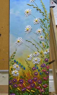 an easel with flowers painted on it in the process of being finished by someone