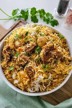 a white bowl filled with rice and meat on top of a wooden cutting board next to parsley