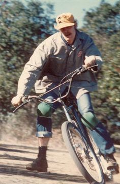 a man riding a bike down a dirt road