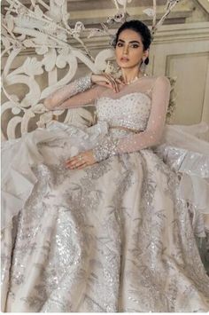 a woman sitting on top of a white chair wearing a dress with silver sequins