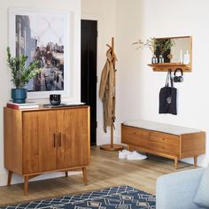 a living room filled with furniture and a wooden cabinet next to a wall mounted coat rack