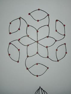 a string art piece with red beads on it and a wire ball in the middle