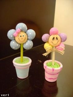 two plastic cups with flowers in them sitting on a black table next to each other