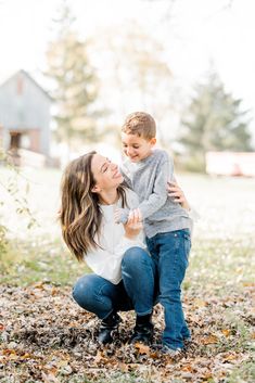 a mother and her son playing in the leaves