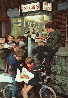 a group of young boys sitting on the back of a bike while eating pizza and talking to each other