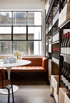 a wine store with shelves full of bottles and glasses on the table, along with two chairs