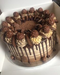 a chocolate cake with white frosting and lots of toppings on top in a box