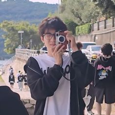 a person taking a photo with a camera in front of people walking on the street