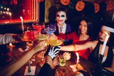 group of people toasting with drinks at halloween party