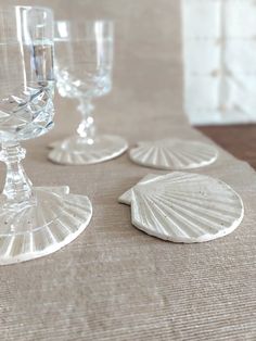 three wine glasses sitting next to each other on top of a cloth covered tablecloth