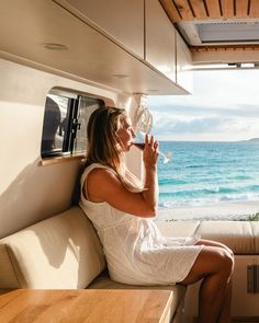 a woman sitting on the back of a boat drinking from a wine glass while looking out at the ocean