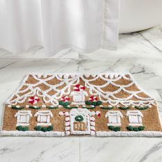 a gingerbread house door mat is on the floor next to a bathtub and shower curtain