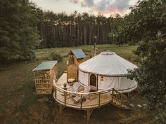 a yurt in the woods surrounded by trees and other small structures with a deck