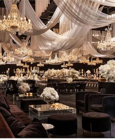 an elegant wedding reception with chandeliers and white flowers on the tables in front of them