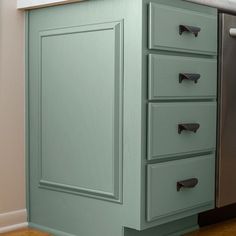 a green cabinet with drawers in a kitchen