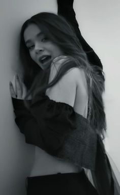 a woman with long hair leaning against a wall