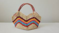 a multicolored straw bag sitting on top of a white table