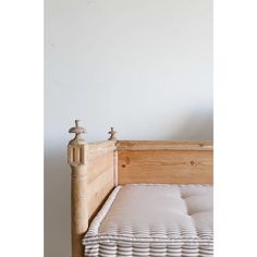 a wooden bed frame with no mattress on top and white walls in the back ground