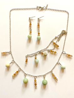 Use these fashionable accessories in pale green, amber, and champagne to create a dressy or casual look. The light sparkling look was handcrafted with natural amazonite gemstones and amber champagne bicone faceted crystal glass beads. This matching set includes a necklace, a pair of earrings, and a bracelet. Length of the necklace and bracelet can be adjusted with metal clasps and extra metal chain. Gemstone - Natural amazonite Beads - Bicone faceted crystal glass beads Color - Pale green, amber, champagne Necklace and bracelet chain - Metal trace chain Necklace and bracelet closure - Lobster claw Earring style - Dangling drop Earring closure - Push back Other materials - Metal jewelry pins and jump rings Length - Necklace, 46 cm; Earrings, 4 cm; Bracelet, 23 cm Elegant Beaded Citrine Jewelry, Elegant Beaded Amazonite Jewelry, Elegant Amazonite Jewelry With Faceted Beads, Elegant Adjustable Amazonite Beaded Necklaces, Amber Czech Glass Jewelry With Faceted Beads, Champagne Necklace, Claw Earrings, Fashionable Accessories, Jewelry Pins