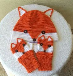 a knitted hat and mittens on top of a white table with a fox motif