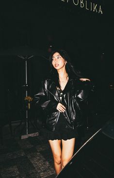 a woman in black leather jacket and short skirt