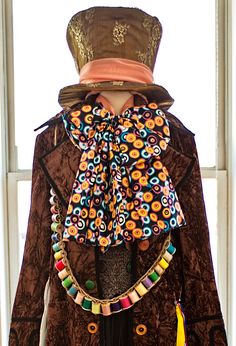 a mannequin wearing a brown jacket and hat with multicolored beads on it