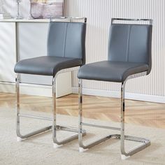 two gray leather chairs sitting on top of a wooden floor