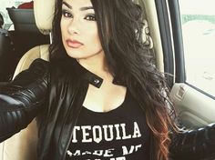 a woman sitting in the back seat of a car wearing a t - shirt that says tequila